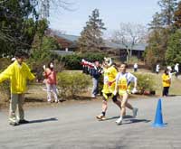 写真：運動広場前のゴールに向かって力走する選手（左にはレースクロック